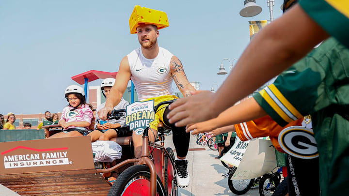 Green Bay Packers tight end Tucker Kraft slaps hands with young fans as he rides to practice at training camp. Green Bay Packers tight end Tucker Kraft slaps hands with young fans as he rides to practice at training camp.