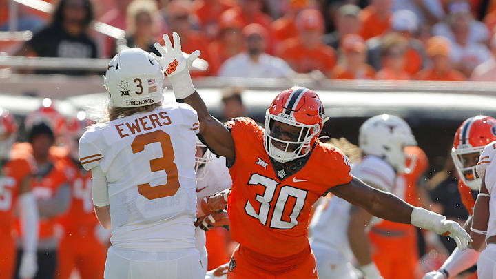 Oklahoma State Cowboys defensive end Collin Oliver (30) puts pressure on Texas Longhorns quarterback Quinn Ewers.