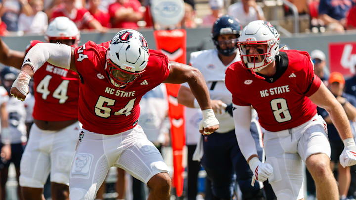 Sep 6, 2025; Raleigh, North Carolina, USA; North Carolina State Wolfpack offensive lineman Rico Jackson (64) celebrates a tackle against Virginia Cavaliers running back J'Mari Taylor (3) during the first half of the game at Carter-Finley Stadium. Mandatory Credit: Jaylynn Nash-Imagn Images