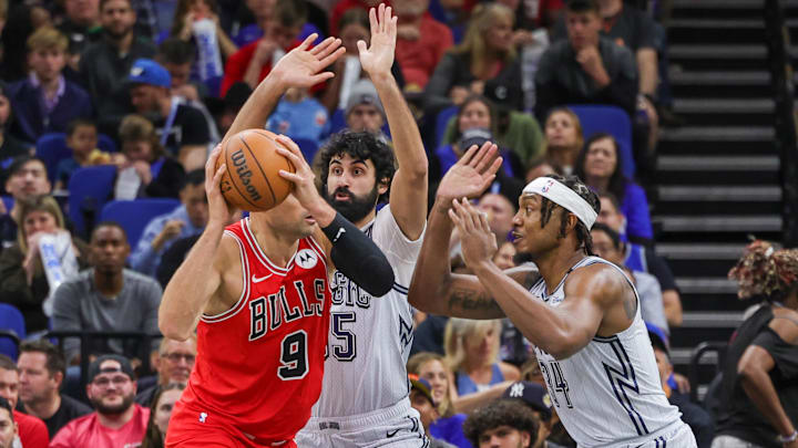 Nov 27, 2024; Orlando, Florida, USA; Orlando Magic center Wendell Carter Jr. (34) and center Goga Bitadze (35) defend Chicago Bulls center Nikola Vucevic (9) during the first quarter at Kia Center. Mandatory Credit: Mike Watters-Imagn Images
