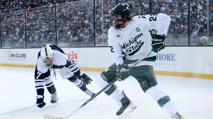Jan 31, 2026; State College, PA, USA; Michigan State Spartans forward Porter Martone (22) moves the puck against Penn State Nittany Lions defenseman Jackson Smith (7) during the second period at Beaver Stadium. Mandatory Credit: Matthew O'Haren-Imagn Images