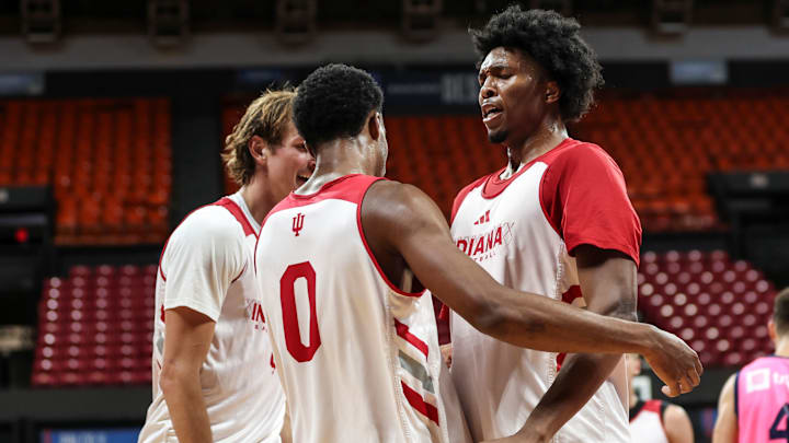 Indiana basketball forward Sam Alexis (right) chest bumps guard Jasai Miles (middle) while forward Reed Bailey (left) smiles.