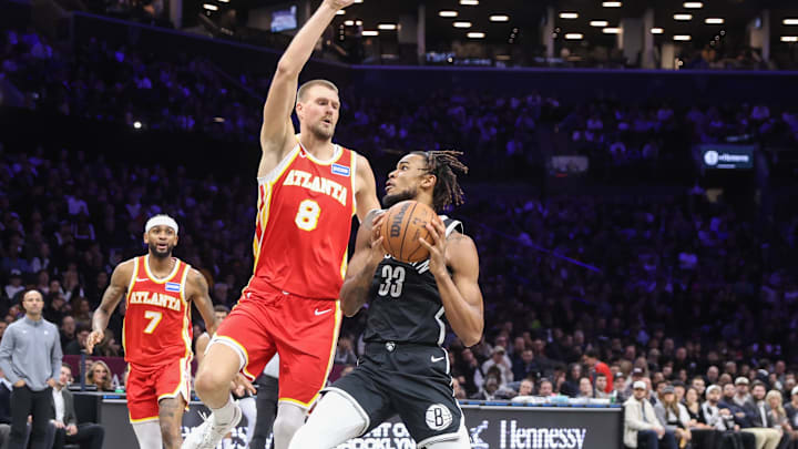 Oct 29, 2025; Brooklyn, New York, USA; Brooklyn Nets center Nic Claxton (33) looks to drive past Atlanta Hawks center Kristaps Porzingis (8) in the second quarter at Barclays Center. Mandatory Credit: Wendell Cruz-Imagn Images