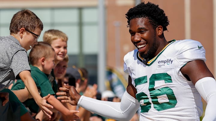Green Bay Packers linebacker Edgerrin Cooper slaps hands with fans as he rides a bicycle to the joint practice vs. Seattle.