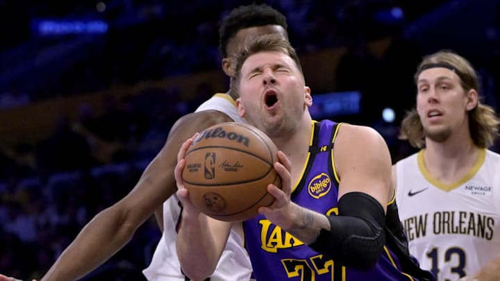 Apr 4, 2025; Los Angeles, California, USA;  Los Angeles Lakers guard Luka Doncic (77) reacts after he was hit in the face driving past New Orleans Pelicans center Yves Missi (21) and forward Bruce Brown (00) in the first half at Crypto.com Arena. Mandatory Credit: Jayne Kamin-Oncea-Imagn Images