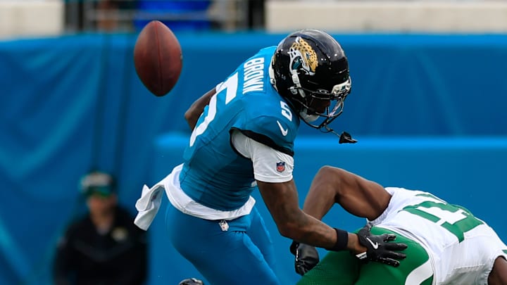 Jacksonville Jaguars wide receiver Dyami Brown (5) turns over the ball as he is hit by New York Jets cornerback Brandon Stephens (21) during the fourth quarter of an NFL football matchup at EverBank Stadium, Sunday, Dec. 14, 2025, in Jacksonville, Fla. The Jaguars defeated the Jets 48-20. 