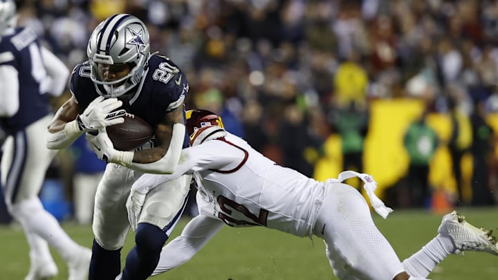 Jan 7, 2024; Landover, Maryland, USA; Dallas Cowboys running back Tony Pollard (20) carries the ball as Washington Commanders safety Terrell Burgess (32) attempts the tackle during the second quarter at FedExField. Mandatory Credit: Geoff Burke-Imagn Images