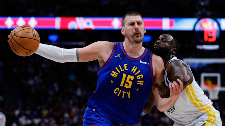 Mar 29, 2026; Denver, Colorado, USA; Denver Nuggets center Nikola Jokic (15) controls the ball as Golden State Warriors forward Draymond Green (23) guards in the third quarter at Ball Arena.