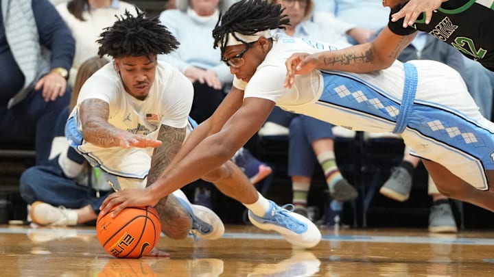 Dec 13, 2025; Chapel Hill, North Carolina, USA; North Carolina Tar Heels guard Derek Dixon (3) and forward James Brown (2) and USC Upstate Spartans forward Jafeth Martinez (12) dive for the ball in the second half at Dean E. Smith Center. Mandatory Credit: Bob Donnan-Imagn Images