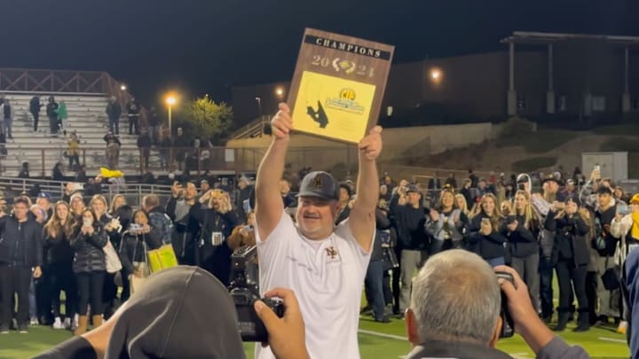 Newbury Park football coach Joe Smigiel raises the CIF championship plaque after beating Murrieta Valley 31-28 on Saturday, November 30, 2024.
