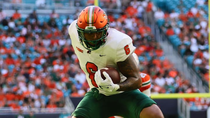 Sep 7, 2024; Miami Gardens, Florida, USA; Florida A&M Rattlers tight end Koby Gross (6) runs with the football past Miami Hurricanes defensive back Jadais Richard (25) during the first quarter at Hard Rock Stadium. Mandatory Credit: Sam Navarro-Imagn Images