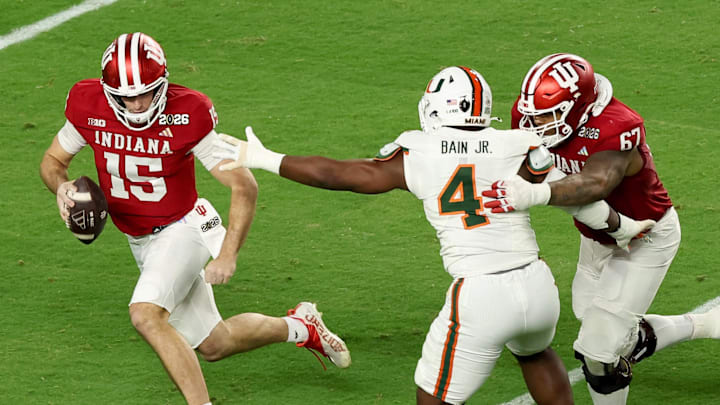 Jan 19, 2026; Miami Gardens, FL, USA; Indiana Hoosiers quarterback Fernando Mendoza (15) scrambles with the ball under pressure by Miami Hurricanes defensive lineman Rueben Bain Jr. (4) in the first quarter during the College Football Playoff National Championship game at Hard Rock Stadium. Mandatory Credit: Kim Klement Neitzel-Imagn Images
