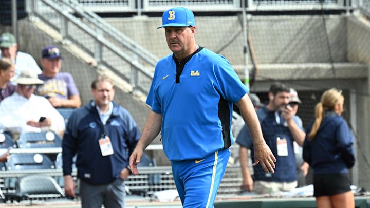 Jun 17, 2025; Omaha, Neb, USA;  UCLA Bruins head coach John Savage (22) walks to the dugout before the restart of the game against the LSU Tigers at Charles Schwab Field. Mandatory Credit: Steven Branscombe-Imagn Images