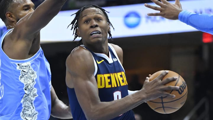 Dec 5, 2024; Cleveland, Ohio, USA; Denver Nuggets forward Peyton Watson (8) drives between Cleveland Cavaliers forward Evan Mobley (4) and guard Donovan Mitchell (45) in the second quarter at Rocket Mortgage FieldHouse. Mandatory Credit: David Richard-Imagn Images