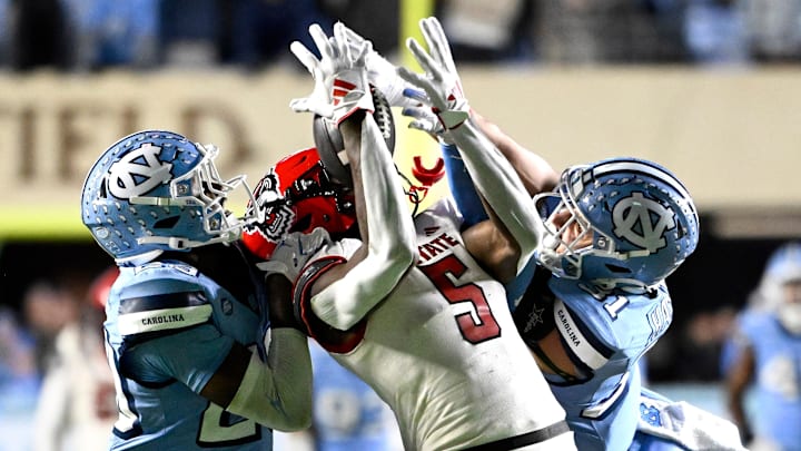Nov 30, 2024; Chapel Hill, North Carolina, USA; North Carolina State Wolfpack wide receiver Noah Rogers (5) catches a 44 yard pass as North Carolina Tar Heels defensive back Marcus Allen (29) and North Carolina Tar Heels defensive back Will Hardy (31) defend in the fourth quarter at Kenan Memorial Stadium. Mandatory Credit: Bob Donnan-Imagn Images Nov 30, 2024; Chapel Hill, North Carolina, USA; North Carolina State Wolfpack wide receiver Noah Rogers (5) catches a 44 yard pass as North Carolina Tar Heels defensive back Marcus Allen (29) and North Carolina Tar Heels defensive back Will Hardy (31) defend in the fourth quarter at Kenan Memorial Stadium. Mandatory Credit: Bob Donnan-Imagn Images
