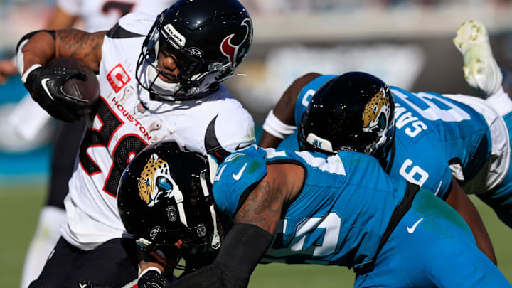 Houston Texans running back Joe Mixon (28), left, is tackled by Jacksonville Jaguars safety Antonio Johnson (26) and safety Darnell Savage (6), back, during the second quarter of an NFL football matchup Sunday, Dec. 1, 2024 at EverBank Stadium in Jacksonville, Fla. [Corey Perrine/Florida Times-Union]