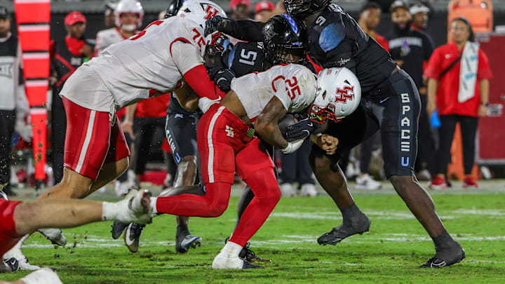 Nov 7, 2025; Orlando, Florida, USA; Houston Cougars running back DJ Butler (25) is tackled by UCF Knights defensive end Malachi Lawrence (51) during the second half at Acrisure Bounce House.