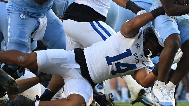 Nov 22, 2025; Chapel Hill, North Carolina, USA; North Carolina Tar Heels running back Demon June (12) is wrapped by Duke Blue Devils defensive end Bryce Davis (14) during the first half at Kenan Stadium. Mandatory Credit: William Howard-Imagn Images Nov 22, 2025; Chapel Hill, North Carolina, USA; North Carolina Tar Heels running back Demon June (12) is wrapped by Duke Blue Devils defensive end Bryce Davis (14) during the first half at Kenan Stadium. Mandatory Credit: William Howard-Imagn Images