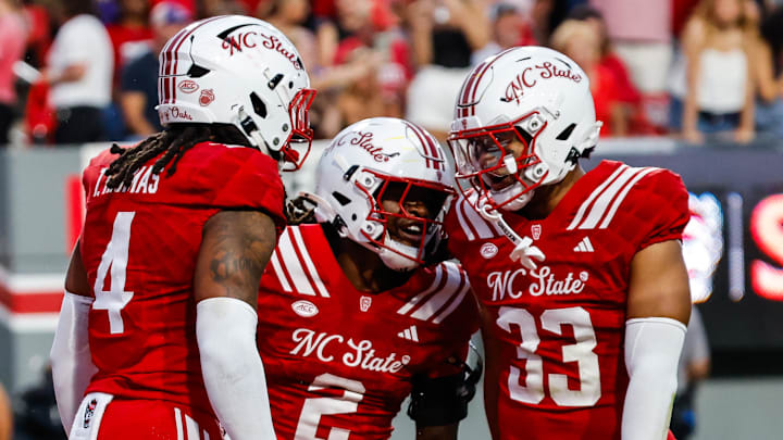 Aug 28, 2025; Raleigh, North Carolina, USA; North Carolina State Wolfpack safety Ronnie Royal III (2),  linebacker Tra Thomas (4) and  linebacker Kenny Soares Jr. (33) celebrate during the first half of the game against East Carolina Pirates at Carter-Finley Stadium. Mandatory Credit: Jaylynn Nash-Imagn Images