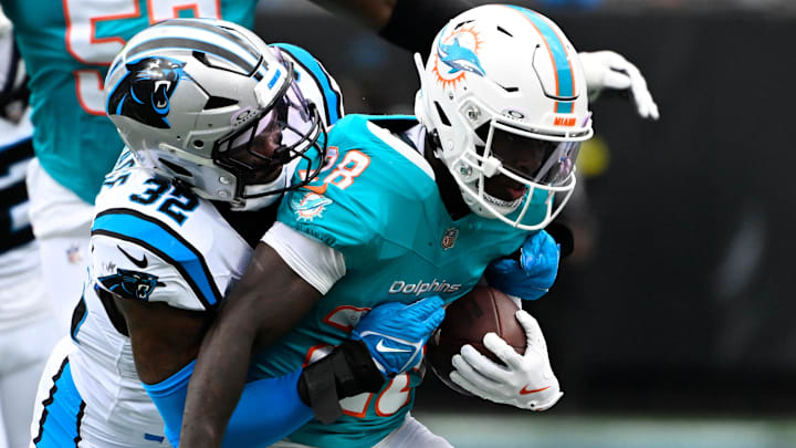 Miami Dolphins running back De'Von Achane (28) runs as Carolina Panthers linebacker Trevin Wallace (32) defends in the first quarter at Bank of America Stadium.