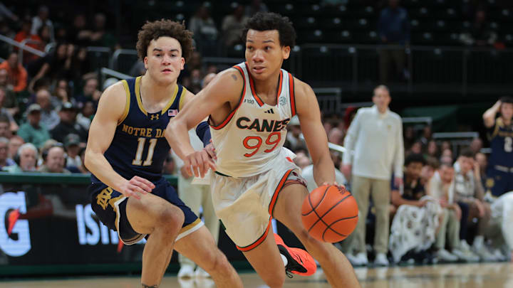 Feb 1, 2025; Coral Gables, Florida, USA; Miami Hurricanes guard Divine Ugochukwu (99) drives to the basket past Notre Dame Fighting Irish guard Braeden Shrewsberry (11) during the second half at Watsco Center. Mandatory Credit: Sam Navarro-Imagn Images