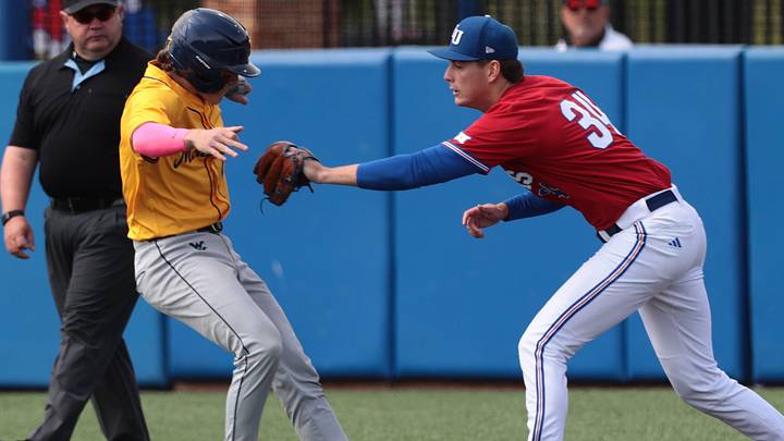 Kansas Jayhawks junior Mathis Nayral (34) looks to tag out West Virginia Mountaineers sophomore Gavin Kelly (2) during the game inside Hoglund Ballpark on May 10, 2026. Kansas Jayhawks junior Mathis Nayral (34) looks to tag out West Virginia Mountaineers sophomore Gavin Kelly (2) during the game inside Hoglund Ballpark on May 10, 2026.