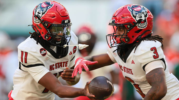 Nov 15, 2025; Miami Gardens, Florida, USA; NC State Wolfpack quarterback CJ Bailey (11) hands off the football to running back Hollywood Smothers (3) during the first quarter at Hard Rock Stadium. Mandatory Credit: Sam Navarro-Imagn Images