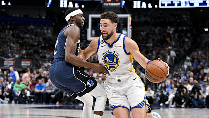 Mar 22, 2023; Dallas, Texas, USA; Golden State Warriors guard Klay Thompson (11) drives to the basket past Dallas Mavericks forward Justin Holiday (0) during the first quarter at the American Airlines Center. Mandatory Credit: Jerome Miron-Imagn Images