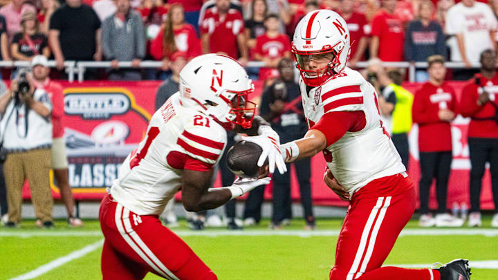 Nebraska Cornhuskers quarterback Dylan Raiola hands the ball off to running back Emmett Johnson.