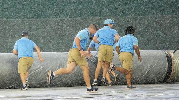 Jun 12, 2025; Kansas City, Missouri, USA; The Kansas City Royals grounds crew scrambles to spread the tarp over the field during the sixth inning rain delay of the game against the New York Yankees at Kauffman Stadium. Mandatory Credit: Denny Medley-Imagn Images
