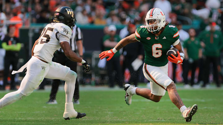 Nov 23, 2024; Miami Gardens, Florida, USA; Miami Hurricanes running back Damien Martinez (6) runs with the football against Wake Forest Demon Deacons defensive back Jamare Glasker (25) during the second quarter at Hard Rock Stadium.