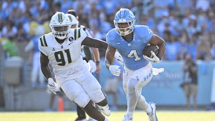 Sep 7, 2024; Chapel Hill, North Carolina, USA; North Carolina Tar Heels running back Caleb Hood (4) with the ball as Charlotte 49ers defensive lineman Dre Butler (91) defends in the third quarter at Kenan Memorial Stadium. Mandatory Credit: Bob Donnan-Imagn Images