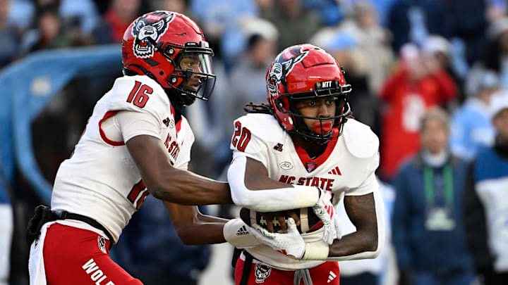 Nov 30, 2024; Chapel Hill, North Carolina, USA; North Carolina State Wolfpack quarterback CJ Bailey (16) hands the ball off to running back Hollywood Smothers (20) the ball in the first quarter at Kenan Memorial Stadium. Mandatory Credit: Bob Donnan-Imagn Images Nov 30, 2024; Chapel Hill, North Carolina, USA; North Carolina State Wolfpack quarterback CJ Bailey (16) hands the ball off to running back Hollywood Smothers (20) the ball in the first quarter at Kenan Memorial Stadium. Mandatory Credit: Bob Donnan-Imagn Images