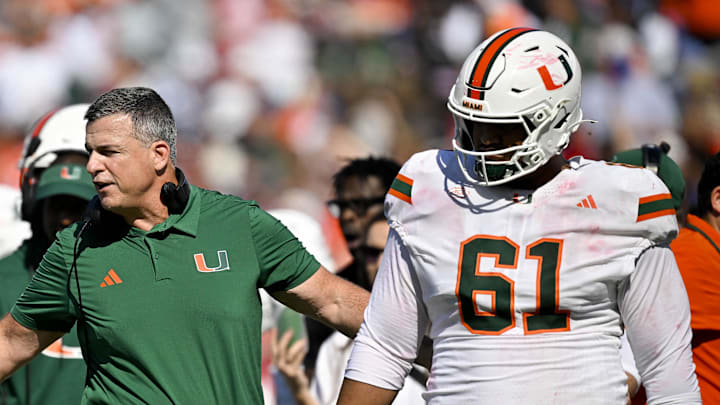Nov 1, 2025; Dallas, Texas, USA;  Miami Hurricanes head coach Mario Cristobal talks to offensive lineman Anez Cooper (73) and offensive lineman Francis Mauigoa (61) during the second half against the SMU Mustangs at Gerald J. Ford Stadium. Mandatory Credit: Jerome Miron-Imagn Images
