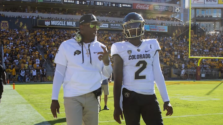 Deion and Shedeur Sanders walk the Colorado sideline.