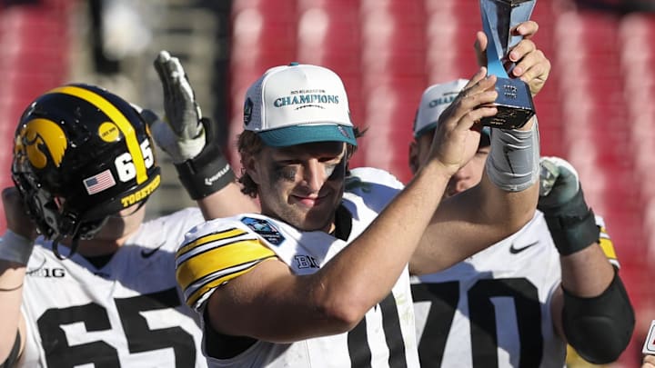 Dec 31, 2025; Tampa, FL, USA; Iowa Hawkeyes quarterback Mark Gronowski (11) is given the MVP trophy after beating Vanderbilt Commodores in the ReliaQuest Bowl at Raymond James Stadium. Mandatory Credit: Nathan Ray Seebeck-Imagn Images