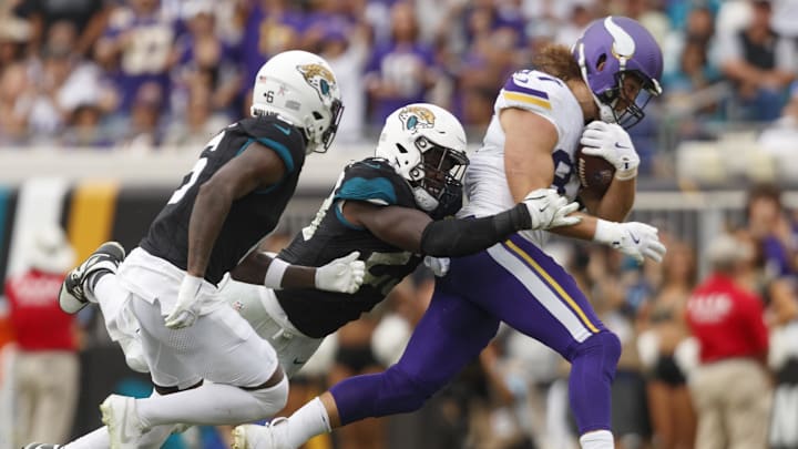 Nov 10, 2024; Jacksonville, Florida, USA; Minnesota Vikings tight end T.J. Hockenson (87) runs through a tackle by Jacksonville Jaguars linebacker Foyesade Oluokun (23) and safety Darnell Savage (6) during the fourth quarter at EverBank Stadium. Mandatory Credit: Morgan Tencza-Imagn Images