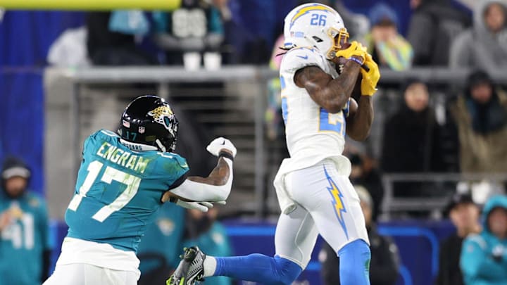 Jan 14, 2023; Jacksonville, Florida, USA; Los Angeles Chargers cornerback Asante Samuel Jr. (26) makes an interception in front of Jacksonville Jaguars tight end Evan Engram (17) during the first quarter of a wild card game at TIAA Bank Field. Mandatory Credit: Nathan Ray Seebeck-Imagn Images