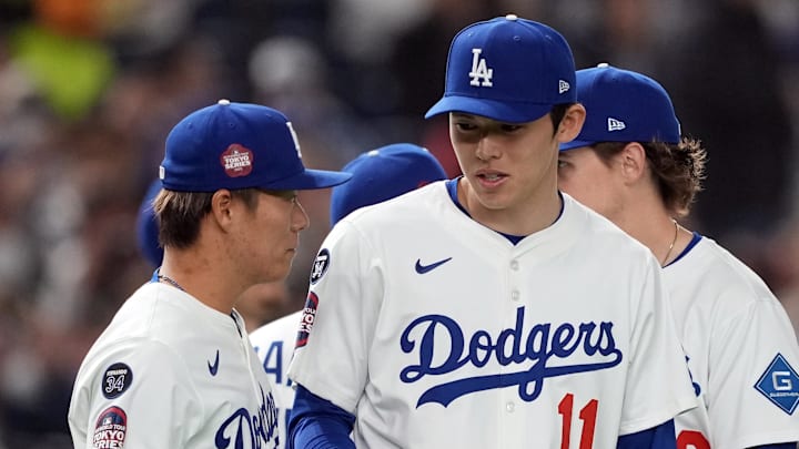 Mar 16, 2025; Bunkyo, Tokyo, Japan; Los Angeles Dodgers pitcher Roki Sasaki (11) talks with pitcher Yoshinobu Yamamoto (left) before the game against the Hanshin Tigers at Tokyo Dome. Mandatory Credit: Darren Yamashita-Imagn Images