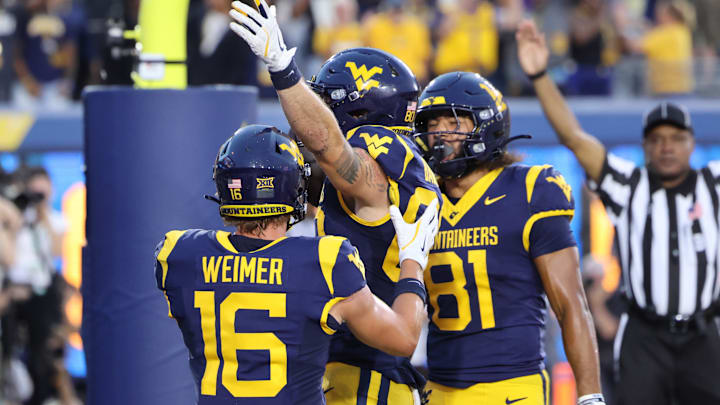 West Virginia University tight end Grayson Barnes celebrates the game-tying touchdown in the fourth quarter with teammates Jacob Barrick (81) and Jeff Weimer (16)