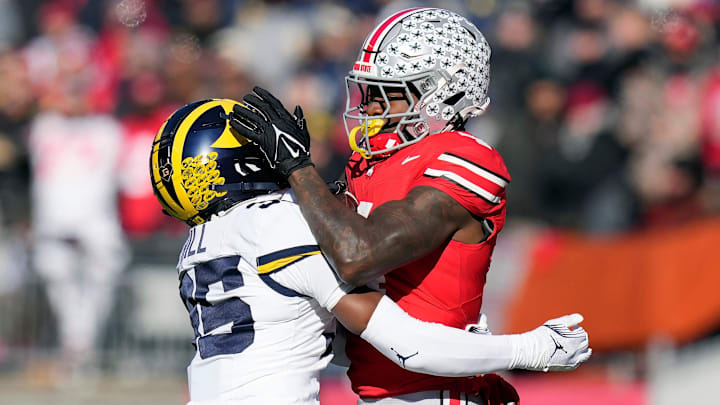 Ohio State Buckeyes wide receiver Jeremiah Smith (4) makes a catch against Michigan Wolverines defensive back Jyaire Hill (35) during the second quarter of the NCAA football game at Ohio Stadium in Columbus on Saturday, Nov. 30, 2024.