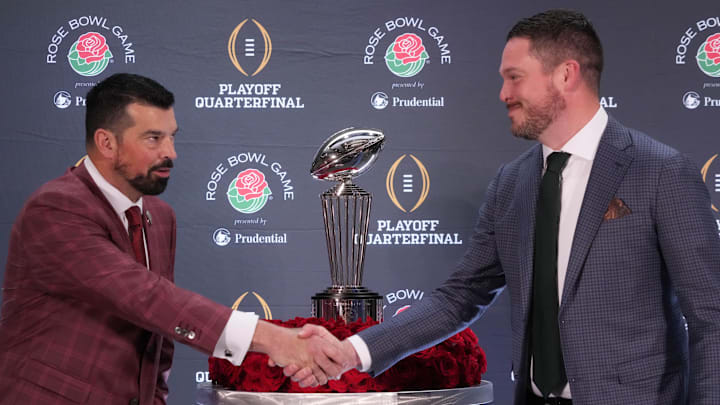 Dec 31, 2024; Los Angeles, California, USA; Ohio State Buckeyes head coach Ryan Day (left) and Oregon Ducks head coach Dan Lanning shake hands with the Leishman Trophy as a backdrop during the Rose Bowl head coaches press conference at Sheraton Grand LA. Mandatory Credit: Kirby Lee-Imagn Images