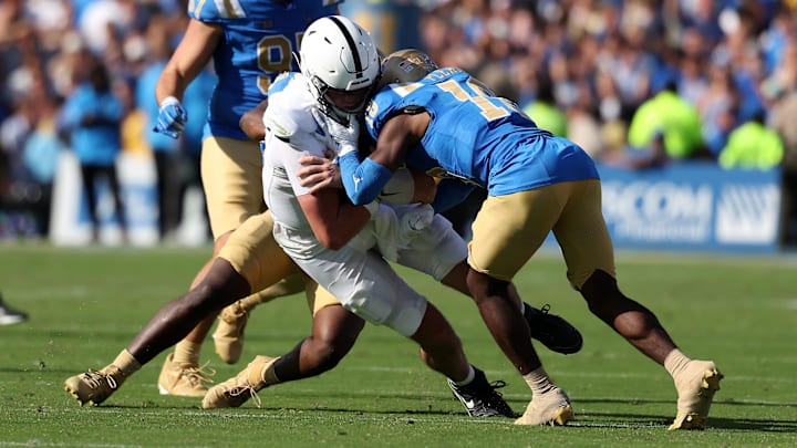 Penn State quarterback Drew Allar takes hits from UCLA linebacker Jalen Woods and defensive back Rodrick Pleasant.