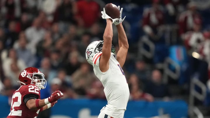 Dec 28, 2023; San Antonio, TX, USA; Arizona Wildcats wide receiver Tetairoa McMillan (4) catches the ball against Oklahoma Sooners defensive back Woodi Washington (5) and defensive back Peyton Bowen (22) in the fist half of the Alamo Bowl at Alamodome. Mandatory Credit: Kirby Lee-USA TODAY Sports