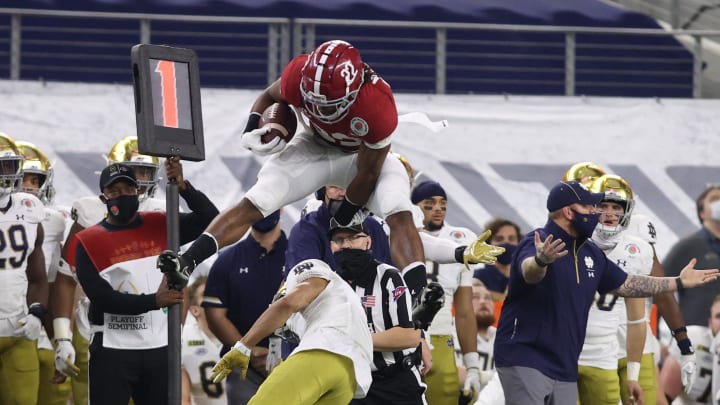 Jan 1, 2021; Arlington, TX, USA; Alabama Crimson Tide running back Najee Harris (22) jumps over Notre Dame Fighting Irish cornerback Nick McCloud (4) in the first quarter during the Rose Bowl at AT&T Stadium.  