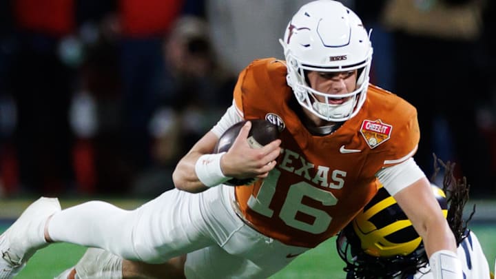 Dec 31, 2025; Orlando, FL, USA; Texas Longhorns quarterback Arch Manning (16) dives forward over Michigan Wolverines defensive back Jordan Young (14) during the second half at Camping World Stadium. Mandatory Credit: Matt Pendleton-Imagn Images