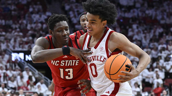 Feb 9, 2026; Louisville, Kentucky, USA;  Louisville Cardinals guard Mikel Brown Jr. (0) drives to the basket against NC State Wolfpack forward Musa Sagnia (13) during the second half at KFC Yum! Center. Louisville defeated N.C. State 118-77. Mandatory Credit: Jamie Rhodes-Imagn Images