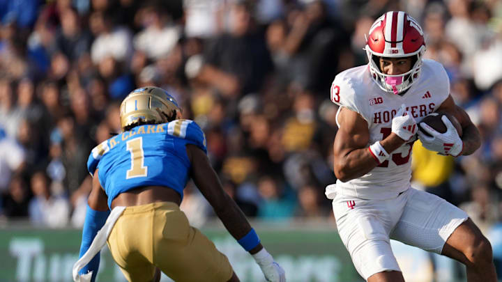Sep 14, 2024; Pasadena, California, USA; Indiana Hoosiers wide receiver Elijah Sarratt (13) carries the ball against UCLA Bruins defensive back Kanye Clark (1) in the first half at Rose Bowl. Mandatory Credit: Kirby Lee-Imagn Images