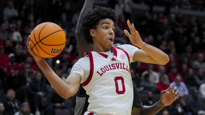 Nov 21, 2025; Cincinnati, Ohio, USA; Louisville Cardinals guard Mikel Brown Jr. (0) passes the ball against Cincinnati Bearcats forward Tyler McKinley (24) in the first half at Heritage Bank Center. Mandatory Credit: Aaron Doster-Imagn Images