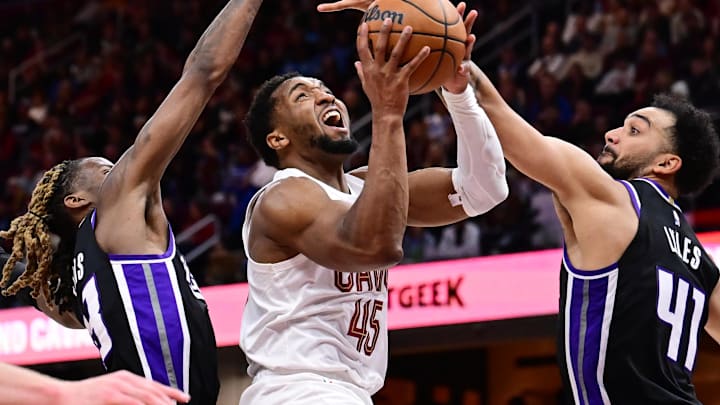 Apr 6, 2025; Cleveland, Ohio, USA; Cleveland Cavaliers guard Donovan Mitchell (45) drives to the basket between Sacramento Kings guard Keon Ellis (23) and forward Trey Lyles (41) during the second half at Rocket Arena. Mandatory Credit: Ken Blaze-Imagn Images